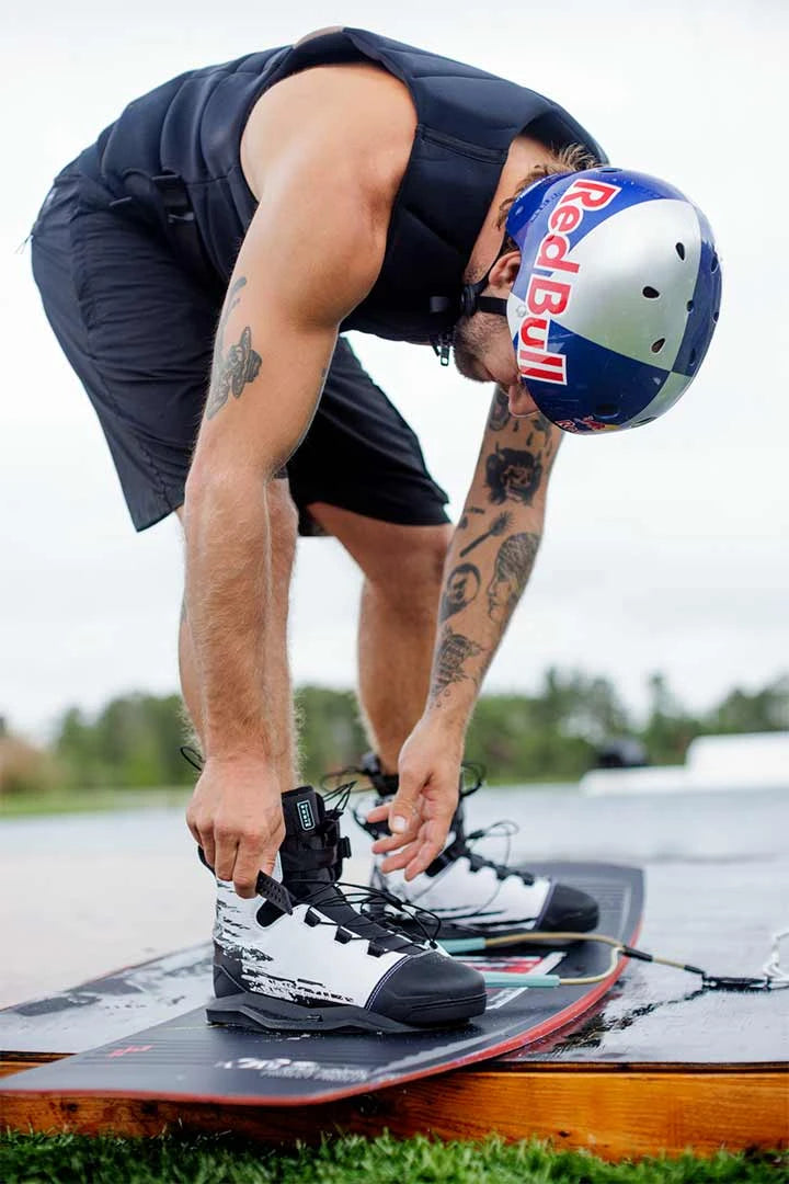 action shot of person putting on the Ronix Kinetik wakeboard boots