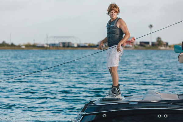 person wearing the 2026 Ronix One Silver Reflective Intuition closed-toe wakeboard boots on a boat